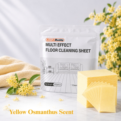 A stand-up pouch of ScrubBuddy Multi Effect Floor Cleaning Sheet is shown on a light marble surface with yellow cleaning sheets fanned out in front and yellow flowers around it. Text at the bottom reads 'Yellow Osmanthus Scent'.